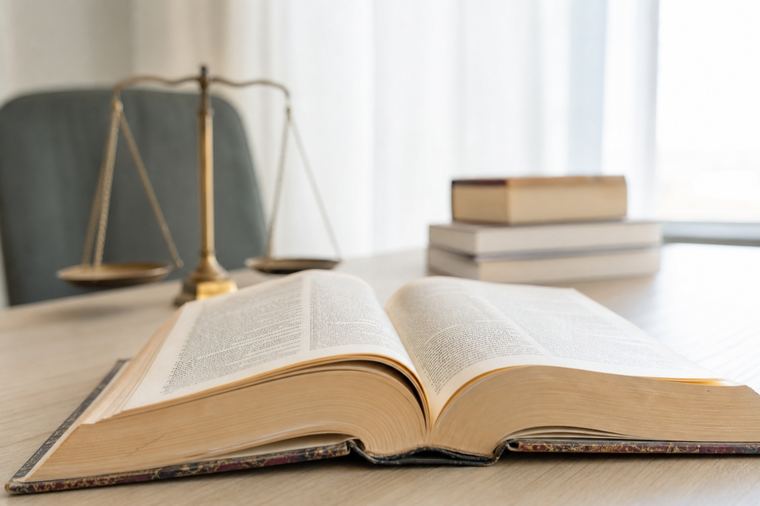 Libro aperto sulle pagine centrali, appoggiato su un piano di legno scuro